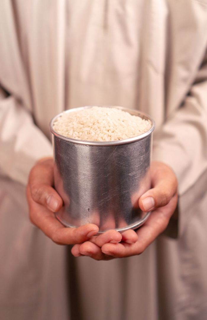 Hands holding a tin cup filled with rice