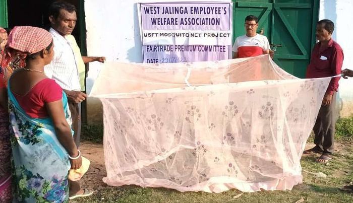 Members unfolding a mosquito net outside the welfare association office